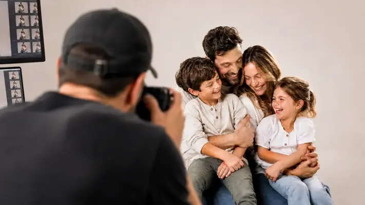 Behind the scenes of a family photoshoot at PM STUDIOS Munich: A photographer captures a joyful family with two children sharing laughter and genuine moments together.
