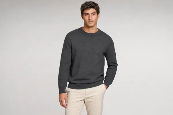 Professionelles Katalog-Shooting bei PM STUDIOS München: Männliches Modell in anthrazitfarbenem Rundhals-Pullover und beiger Hose vor einem neutralen hellgrauen Studiohintergrund; ideal für E-Commerce und Mode-Lookbooks.