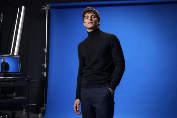 Editorial photography 4 Behind the scenes of a men's editorial fashion shoot at PM STUDIOS Munich: Male model in a black turtleneck posing against a vibrant blue backdrop, featuring a digital capture workstation.