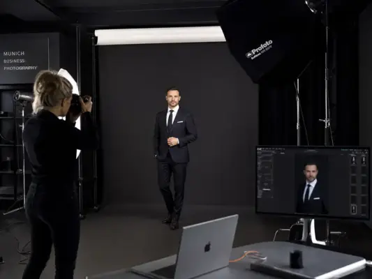 Business photos 2 Behind the scenes at PM STUDIOS Munich: A professional photographer shooting a businessman in a suit using high-end Profoto studio equipment and tethered capture.